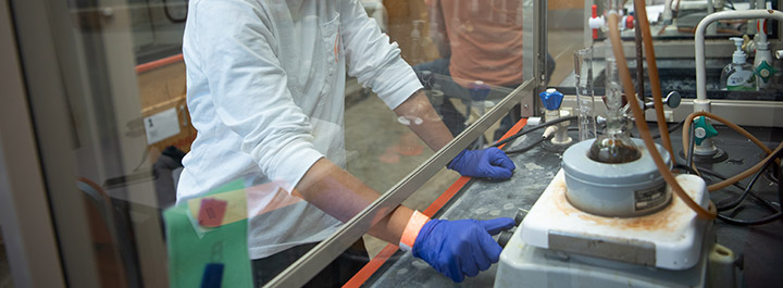 人戴着手套的手plexi盾后面使用实验室设备