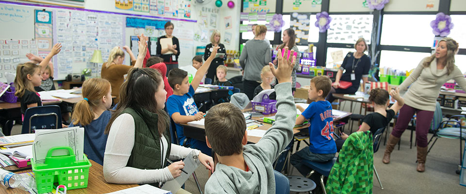 学生在课堂上举手,与一群教育者参与。