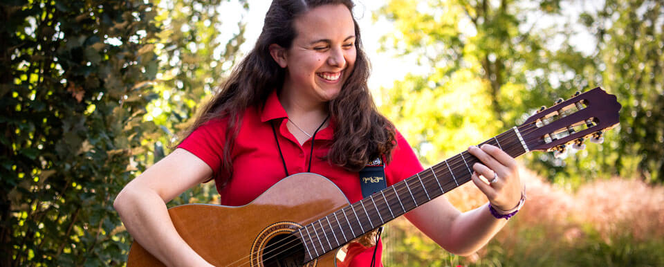 一位音乐治疗专业的学生一边弹吉他一边微笑。
