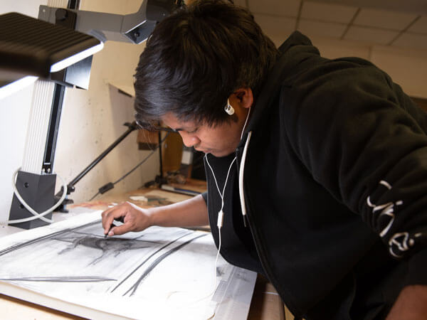 一个画画的学生用炭笔画画。