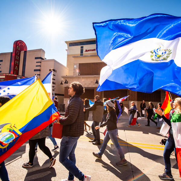 国际学院的学生举着各自国家的国旗走在劳动节游行队伍中。
