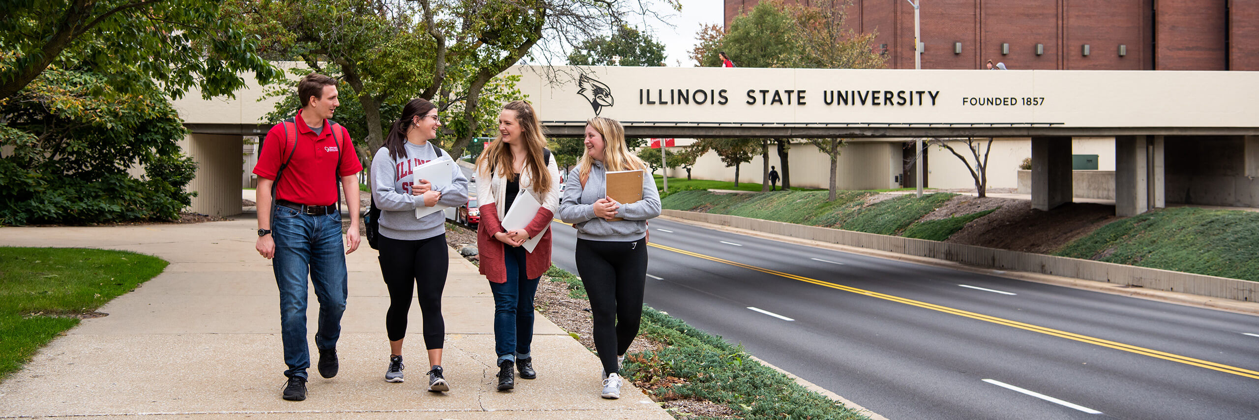 四名伊利诺伊州立大学的学生走在学院大道大桥前的小路上。