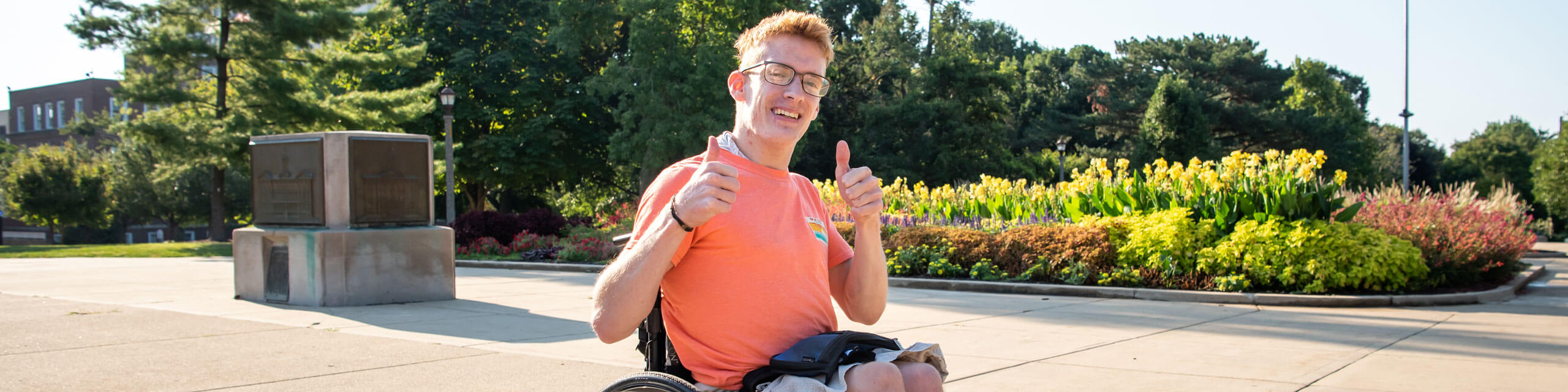 一个学生坐在轮椅上给相机两个竖起大拇指。