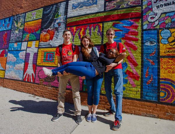 学生在Uptown Normal的壁画前摆姿势。