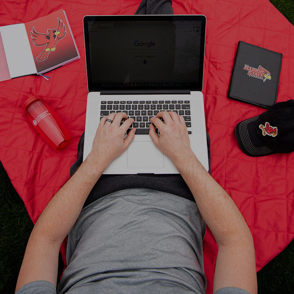 学生坐在红毯子上使用笔记本电脑。