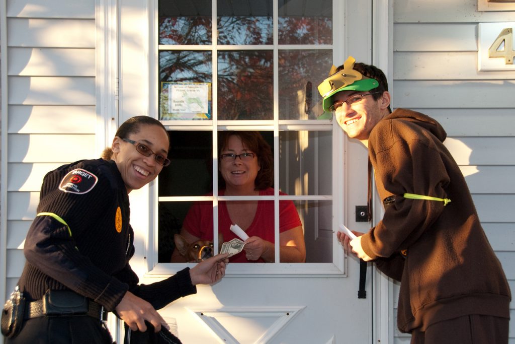 两个学生站在一扇门从居民收集捐款
