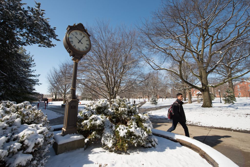 一名学生走过伊利诺斯州立大学广场上的时钟。