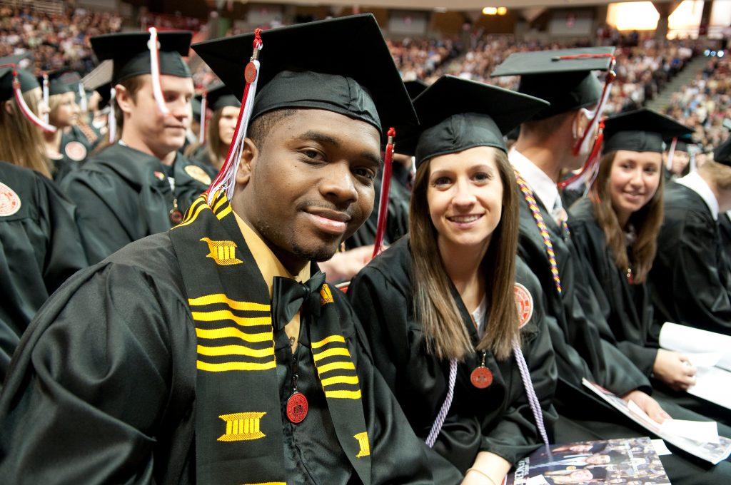 伊利诺伊州立大学毕业典礼上，学生们戴着学士帽和学士服微笑着摆姿势