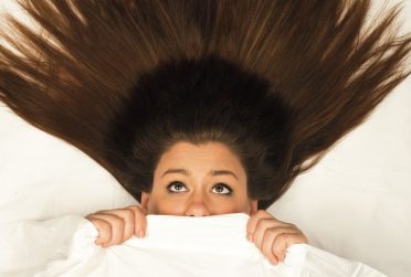 红鸟学者2016秋季封面无短信的女人在床单下看起来害怕，头发伸展过她的头