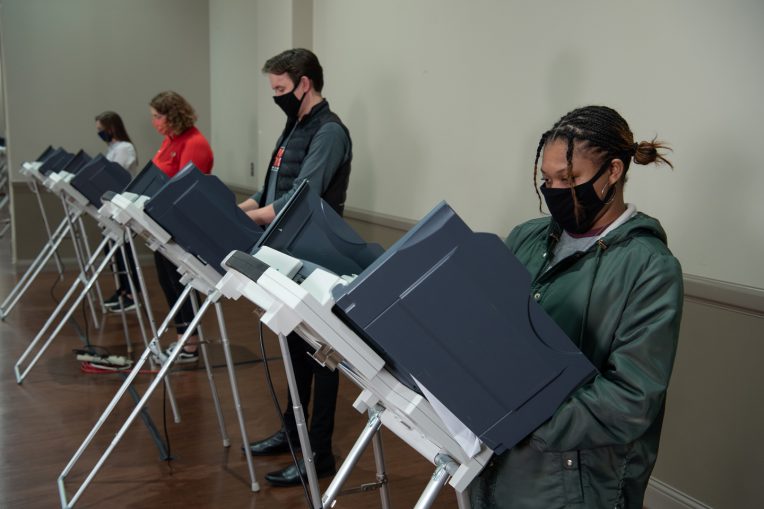 蒙面选民在远程投票机前投票