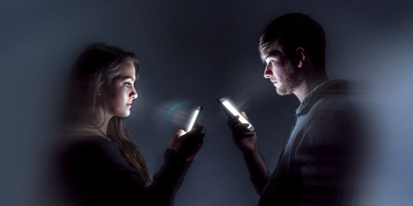 伊利诺斯州杂志封面两人在一个黑暗的房间面对面但盯着他们的智能手机
