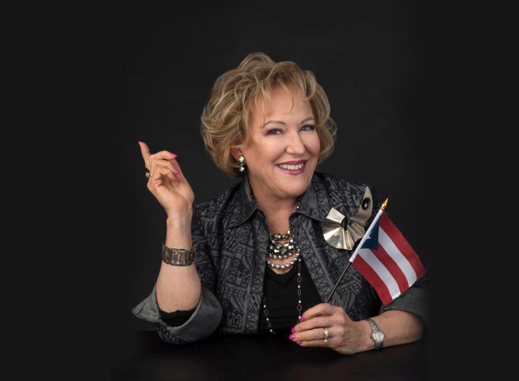 博士的画像Leida Javier-Farrell微笑,举起她的食指和波多黎各国旗。