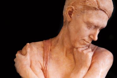 伊利诺斯州立大学校友杂志2017年夏季封面展示了一个男人的玻璃雕塑，一只手放在下巴下，另一只手抓住他的肩膀