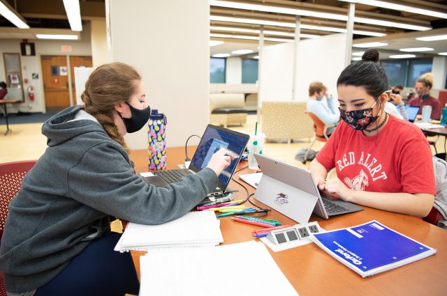 两名学生在米尔纳图书馆三楼的桌子前工作的照片