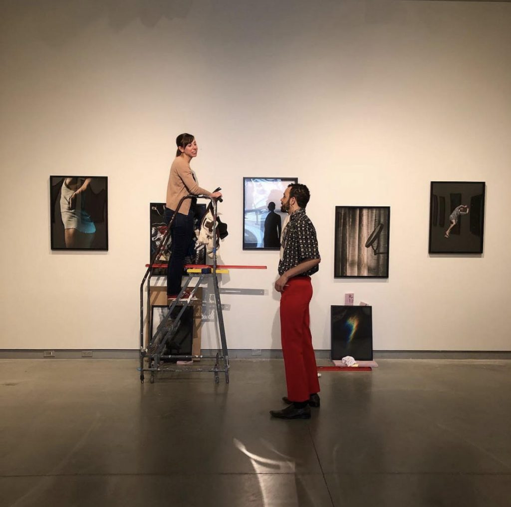 坎德拉·派茨和学生谢尔登·古奇在大学画廊安装艺术家展览