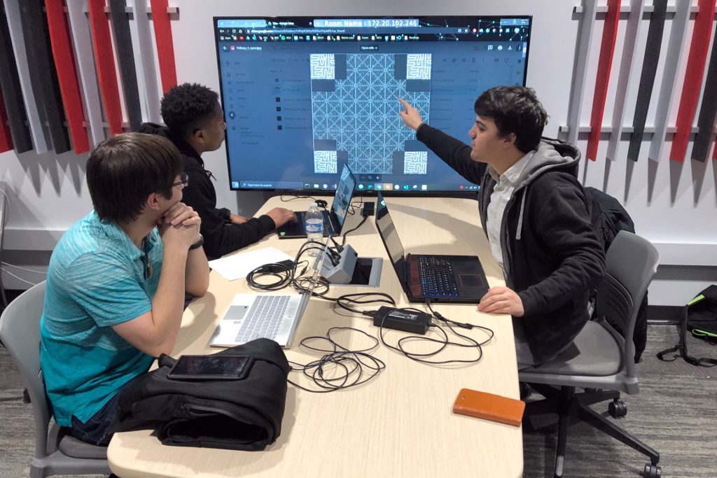 三个学生研究大型计算机屏幕
