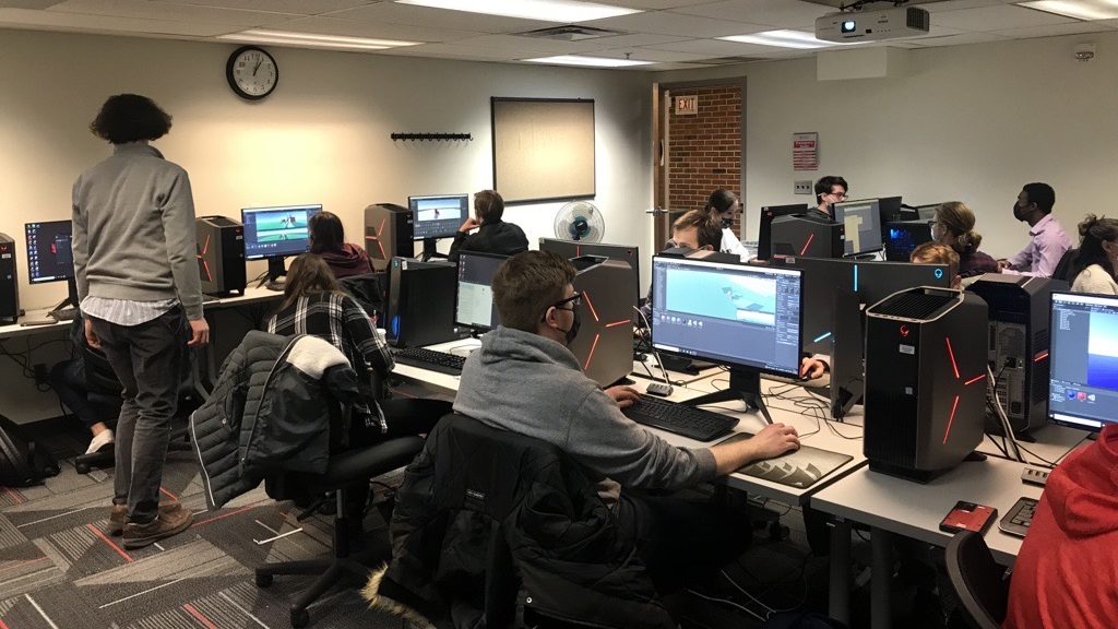 一群学生坐在教室计算机实验室与强大的机器可以处理他们正在与虚拟现实工具