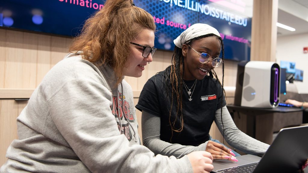 两名女学生一起在笔记本电脑上解决一个技术问题