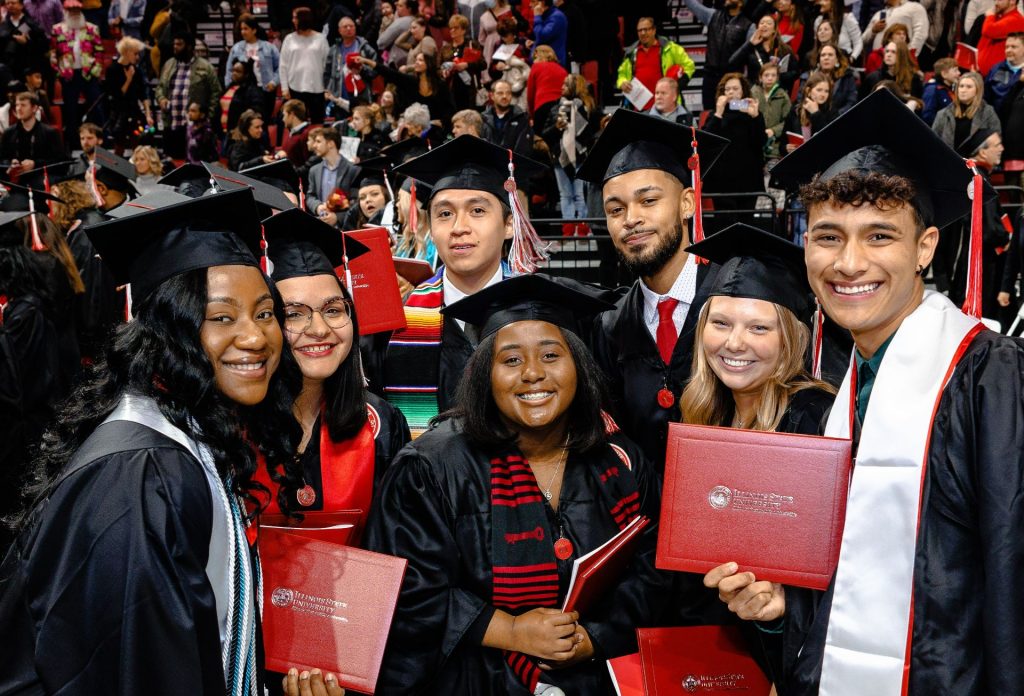 一组七名学生戴着帽子和长袍，拿着毕业证