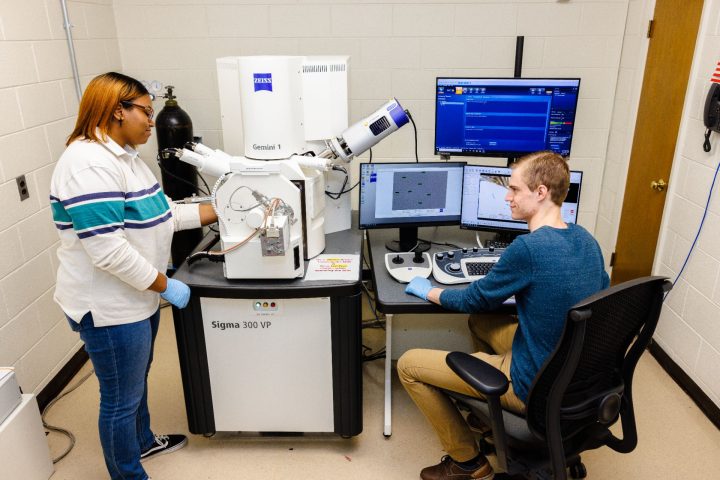 两个学生在实验室里用一个大显微镜工作