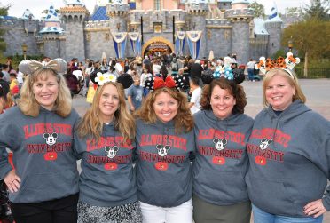 五个校友摆姿势在迪斯尼世界穿同样的伊利诺斯州和迪斯尼品牌的运动衫