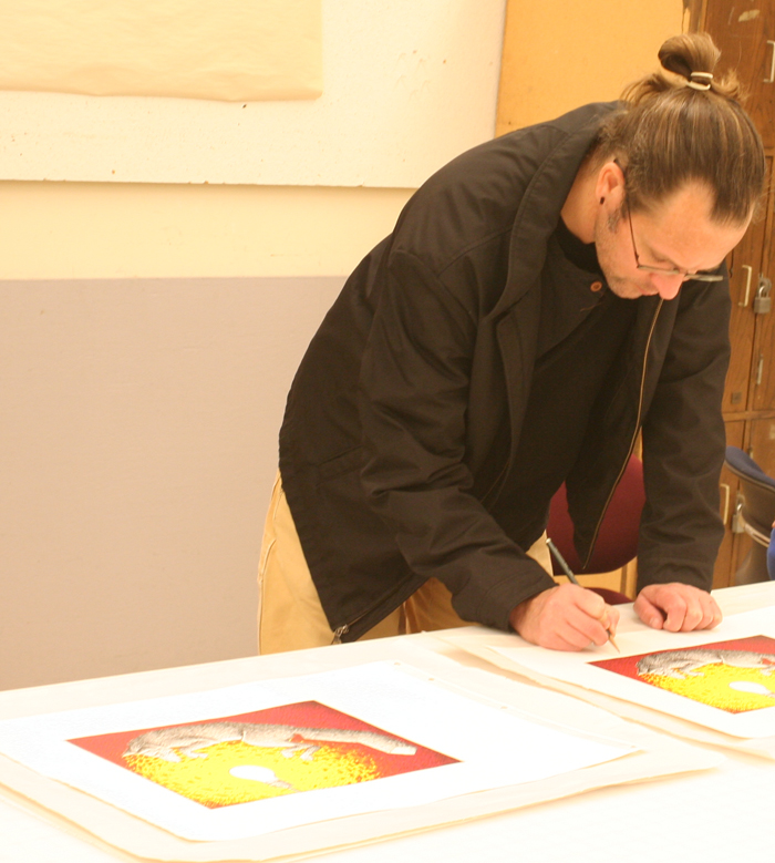 艺术家杰森·沃克在普通版工作室为他的作品签名。